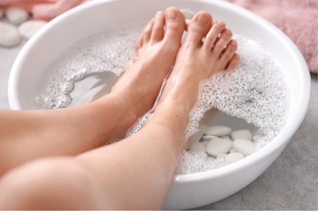 Soaking feet in warm water with Epsom salt to soften corns and calluses